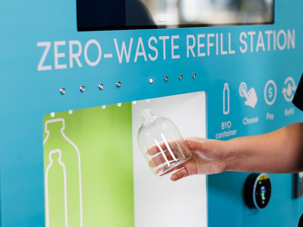 A hand with reusable bottle getting refill at zero waste refill station